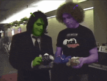 a man wearing a purple shirt with the word nirvana on it is standing next to a man with green hair