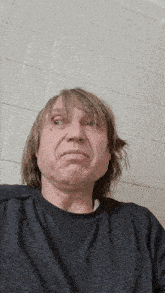 a man with long hair is wearing a gray shirt