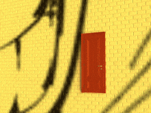a yellow brick wall with a red door and a shadow of an arrow