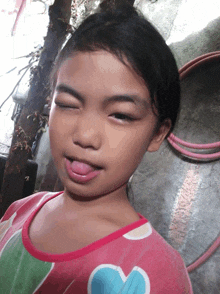 a little girl with a heart on her shirt sticks her tongue out