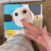 a person 's hand is reaching out towards a drawing of a spongebob character