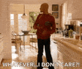 a man in a red sweater is standing in a kitchen holding a baby and a bottle .
