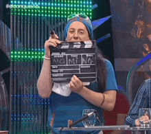 a woman in a blue shirt is holding a clapper board that says " no mi na "