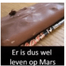 a close up of a chocolate bar with the words er is dus wel leven op mars written on it .