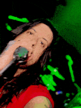 a woman singing into a microphone with a green background