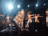 a group of people are dancing on a stage and one of them is wearing a costume that looks like a rocket