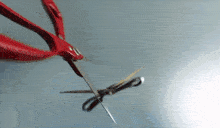 a pair of scissors with red handles cutting a piece of fabric