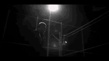 a black and white photo of a person standing on a fence