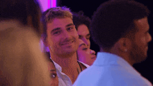 a group of people are standing in a dark room and a man is smiling .