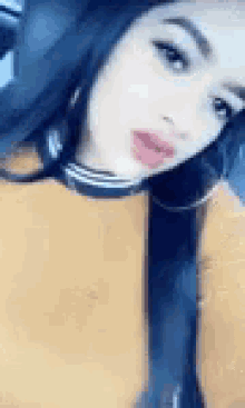 a woman is taking a selfie in a car while wearing a yellow sweater and hoop earrings .