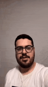 a man with a beard and glasses is taking a selfie with his cell phone .