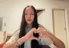 a woman with long hair making a heart with her hands
