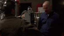 a man wearing a welding helmet is talking to another man with a sony logo in the background