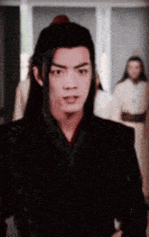 a man with long hair is standing in a room