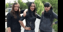 three women are posing for a picture together and one has her arm around the other 's shoulder