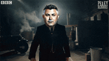 a poster for peaky blinders shows a man in a suit holding a knife