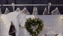 a wreath in the shape of a heart is hanging on a clothes rack