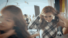 a woman in a plaid shirt is adjusting her hair