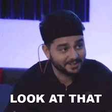 a man with a beard and headphones is making a funny face and saying `` look at that ''