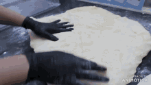 a person wearing black gloves is touching a piece of dough with the words made in animatica visible
