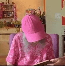 a woman with blue hair and a pink hat is sitting in a chair reading a book .