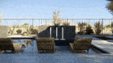 a fence surrounds a swimming pool with chairs and a fountain in the middle