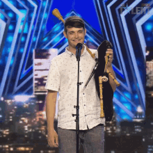 a young man stands in front of a microphone holding a bagpipe in front of a sign that says espana talent