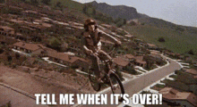 a man riding a bike on a hill with the words tell me when it 's over