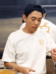 a man wearing a white t-shirt with a logo on the front