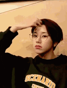 a woman wearing glasses and a green sweater with the word scenario on it