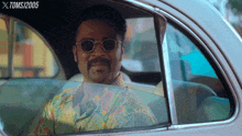 a man wearing sunglasses is sitting in a car with a toms / 2005 watermark