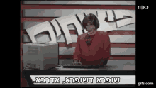 a woman in a red jacket is sitting at a desk in front of a computer and a sign that says 11