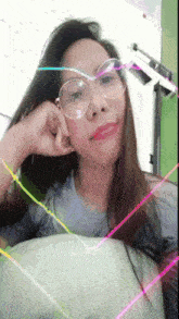 a woman wearing glasses looks at the camera with a colorful background
