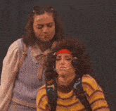 a woman wearing a backpack with dinosaurs on it looks at another woman