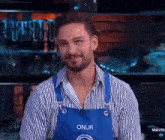 a man wearing a blue apron with the name onur on it
