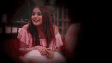 a woman in a pink off the shoulder top is smiling and waving her hand