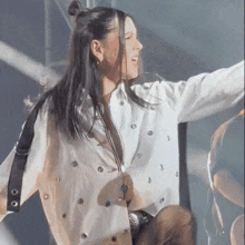 a woman in a white jacket is singing into a microphone on a stage