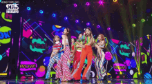 a group of women are dancing on a stage with a wow sign in the background .