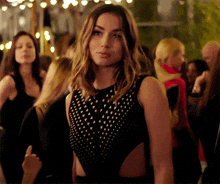 a woman in a black bodysuit is standing in a crowd