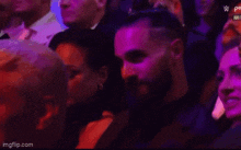 a man and a woman are sitting in a crowd of people with purple lights behind them .