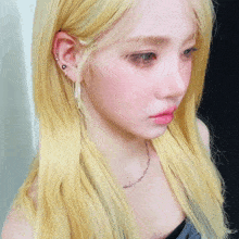 a close up of a woman with blonde hair and a necklace
