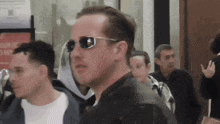 a man wearing sunglasses is walking in a crowded area