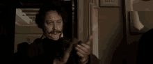 a man with a mustache is standing in a dark room .