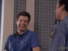 a man in a blue shirt is laughing while standing next to a police officer ..