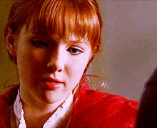 a woman with red hair is wearing a white shirt and a red jacket
