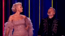 a man and a woman are standing next to each other on a stage and the woman is laughing .