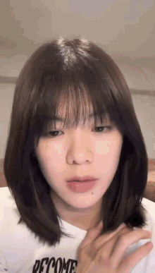a young woman with short hair and bangs is wearing a white t-shirt .