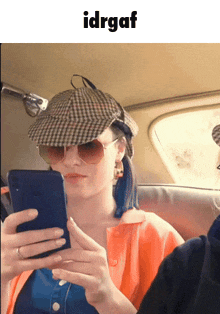 a woman wearing a hat and sunglasses is looking at her cell phone with the word idrgaf below her