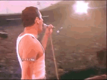 a man singing into a microphone with a crowd behind him