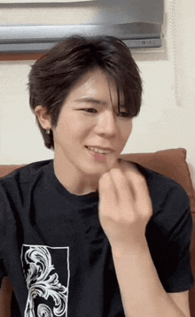 a young man wearing a black t-shirt with a white graphic on it